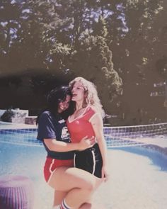 two women are hugging in front of a pool