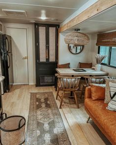 a living room and dining area in a mobile home with wood flooring, couches, table and chairs