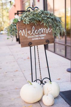 two white pumpkins sitting next to a welcome sign