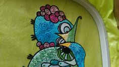 a blue bird with flowers on it's head is embroidered onto a green pillow