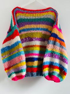 a multicolored sweater hanging on a white hanger, with the top half open