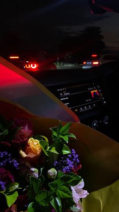 a bouquet of flowers is sitting in the passenger seat of a car at night time