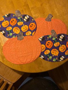 three pumpkin place mats sitting on top of a wooden table