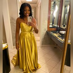 a woman in a gold dress taking a selfie with her cell phone while standing in front of a mirror