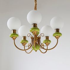 a green and white chandelier hanging from a wooden ceiling fixture with five lights