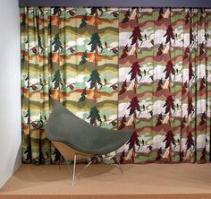 a chair sitting on top of a wooden floor next to a window covered in colorful curtains