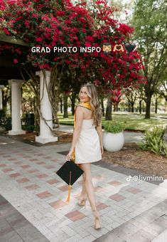 a woman in a white dress is holding a black purse and posing for the camera