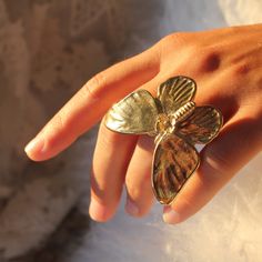 A real life sized butterfly sits atop a half round comfort fit ring suitable for a Queen. The size is 50 mm x 45 mm large enough to feel as if an actual butterfly landed on your hand. A singular flower sits atop this well balanced composition that has been polished to perfection. In the language of spirit animals butterflies represent metamorphosis, total transformation and ultimate freedom. They also symbolize rebirth, hope, bravery, and send the spiritual message that positive change is transp Singular Flower, Cosmo Flower, Butterfly Rings, Gold Butterfly Ring, Bug Jewelry, Yellow Bra, Elizabeth Jewelry, Big Butterfly, Spirit Animals