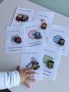 a child's hand reaching for some stickers on top of a white table