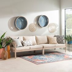 a living room filled with lots of furniture next to a large glass window and potted plants