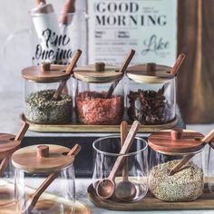 various spices and seasonings in glass containers with wooden spoons on a counter top