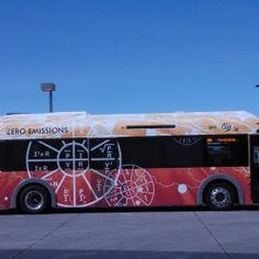 a red and black bus parked in front of a parking lot next to a building