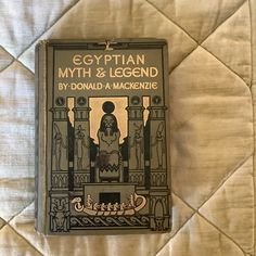 an old book with egyptian mythology and legend written on it sitting on top of a bed