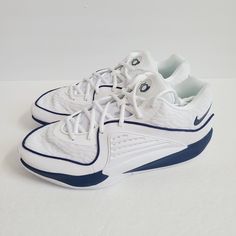 a pair of white and blue tennis shoes on a white surface with the shoe laces down