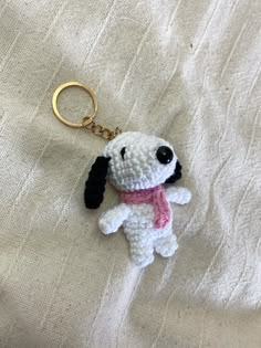 a crocheted dog keychain with a pink scarf around it's neck