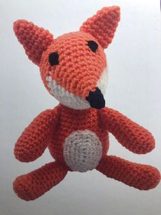 an orange knitted stuffed animal with black eyes