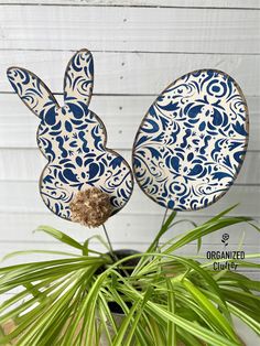 two blue and white ceramic rabbits sitting on top of a potted plant next to a wooden