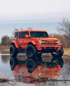 an orange jeep is parked in front of a body of water