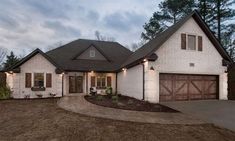 a white brick house with brown shutters and two garage doors on the front door