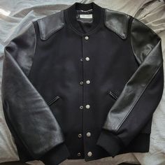 Saint Laurent Men's Size 52 (Italian) Can Be Unisex Fits Smaller - Medium/Slim Large Black Virgin Wool & Lamb Leather Jacket Has Been Worn To Church Once And Only Tried On In The House A Few Times. It Appears New As Purchased And I Just Took The Tags Off Recently. Has Been Sitting In Closet Unused Since Purchase. Size 52 But I'd Recommend For Someone In The 48-50 Range Although I Am 6'2" 200 Lbs And It Fits Me. Little Snug. It Is A Beautiful Jacket That I Will Be Sad To Let Go. I Can Give Measur Designer Black Leather Jacket For Streetwear, Ysl Varsity Jacket, Designer Black Wool Outerwear, Black Designer Wool Outerwear, Luxury Black Wool Outerwear, Ysl Leather Jacket Men, Saint Laurent Leather Jacket Men, Luxury Black Leather Jacket With Double-lined Hood, Luxury Leather Jacket With Double-lined Hood For Men