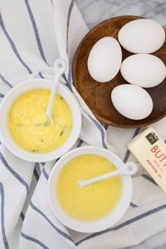 eggs, butter and yogurt sit on a towel next to a wooden bowl