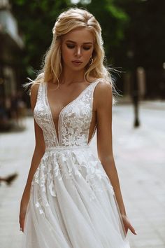 a woman is walking down the street wearing a white wedding dress with flowers on it