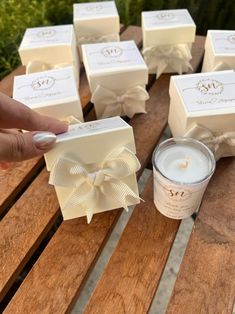 a person holding a candle in front of some small boxes on a wooden table with bows