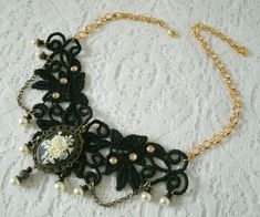 "This beautiful necklace has an antique gold filigree pendant with rose cameo setting, pearl beads, gold plated bead caps, seed beads, metal chain and black lace with rhinestone accents. It is 13\" long adjustable to 17\" long. Lobster clasp."