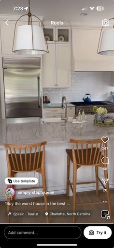 two wooden chairs sitting in front of a white kitchen island with marble counter tops and stainless steel appliances