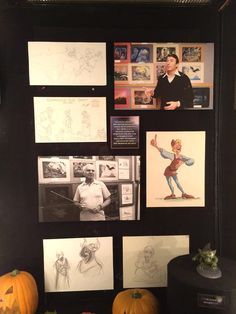 some pictures and pumpkins are on display in front of a black wall with drawings