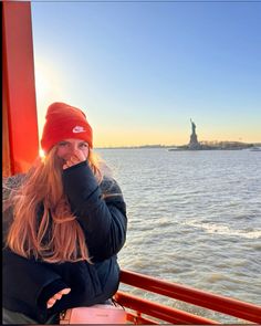 a woman sitting on top of a boat next to the statue of liberty