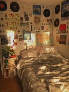 an unmade bed with lots of pictures on the wall