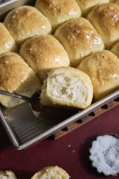 a baking pan filled with rolls on top of a red countertop next to sugar