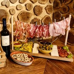 an assortment of meats and cheeses on a table next to a bottle of wine