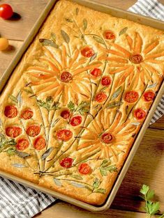 a pan filled with food on top of a wooden table next to tomatoes and other vegetables