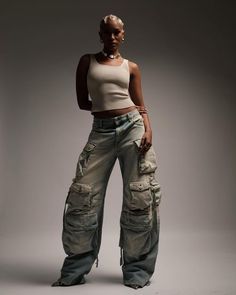 a woman standing in front of a gray background wearing cargo pants and a tank top