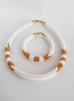 White and gold beaded necklace , African beaded necklace , Beaded necklace with matching bangle , Jewelry from Africa This necklace is 100% handcrafted using original fine beads. *Necklace comes with 1 matching bangle. The necklace is 18 inches long( round the neck). **Buy multiple items and pay shipping for 1 item only.The rest ships free. Thank you for visiting my shop. More neckleces here; https://www.etsy.com/shop/TribalTess?ref=seller-platform-mcnav&section_id=21306083 Back to my shop; Traditional White Necklace With Tiny Beads, Traditional Gold Beaded Chain Bracelets, White And Gold Beads For Jewelry Making, Handmade White Round Beads Jewelry, White Gold Beads For Jewelry Making, Traditional White Jewelry With Gold Beads, White Jewelry With Large Beads For Gifts, White Necklaces With Tiny Beads, White Necklaces With Tiny Round Beads