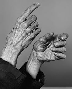 an old man's hands reaching up into the air to catch something with his fingers