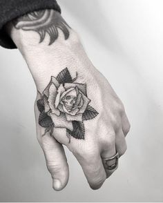 a black and white rose tattoo on the left hand