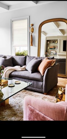 a living room filled with furniture and a large mirror on the wall above it's coffee table