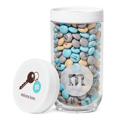 a jar filled with lots of different colored candies next to a white container that has a key on it