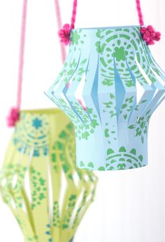 two paper lanterns hanging from strings on the ceiling, one is blue and green with pink flowers