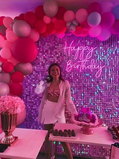 a woman standing in front of a table with cupcakes and balloons on it