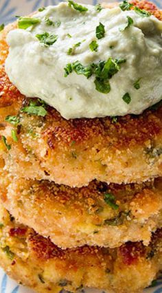 a stack of crab cakes topped with sour cream and chives on a blue and white plate