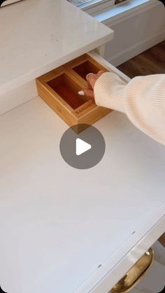 a person opening a drawer on top of a white table