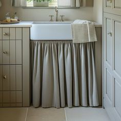 a white sink sitting under a window next to a counter top with a towel on it