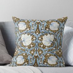 a blue and brown pillow on top of a couch with white flowers in the middle