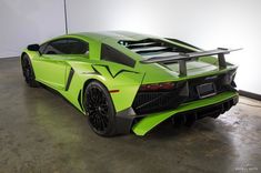 a lime green sports car parked in a garage next to a white wall with black lettering on it