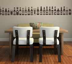 two chairs sitting in front of a wooden table with bottles on the wall behind them