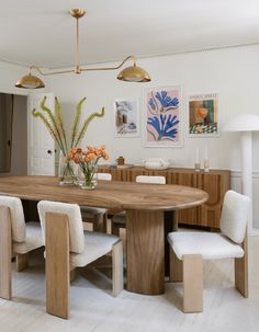 a dining room table with four chairs and a vase full of flowers on the table